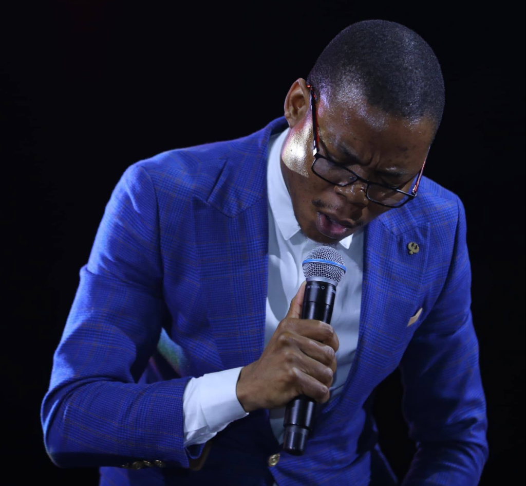 A worship singer in a blue suit holding a microphone