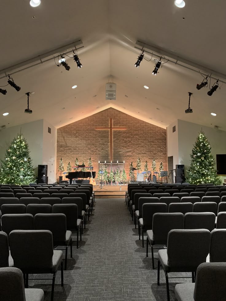 The inside of a church sanctuary with rows of chairs facing a wooden cross and stage