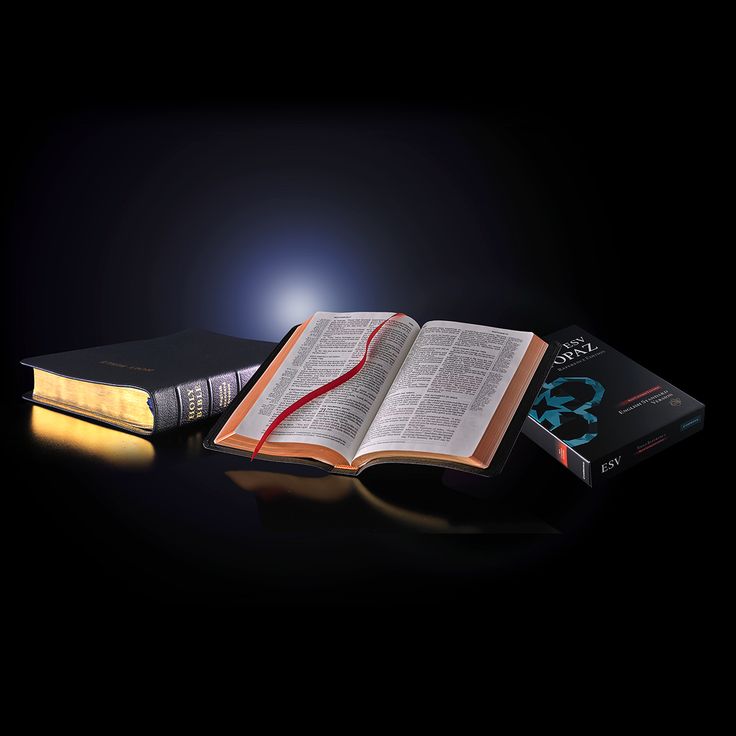 An open King James Bible with a red ribbon marker, beside a closed Bible and a Bible box